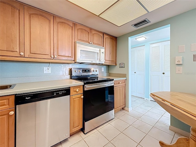 kitchen featuring light tile patterned flooring, visible vents, stainless steel appliances, and light countertops