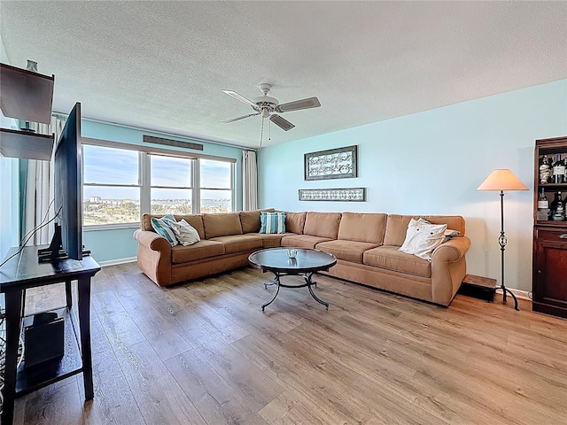 living room with a textured ceiling, light wood-style flooring, and a ceiling fan