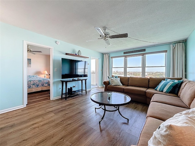 living room featuring a textured ceiling, a ceiling fan, and wood finished floors