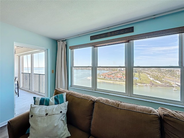 living area featuring a water view and a textured ceiling