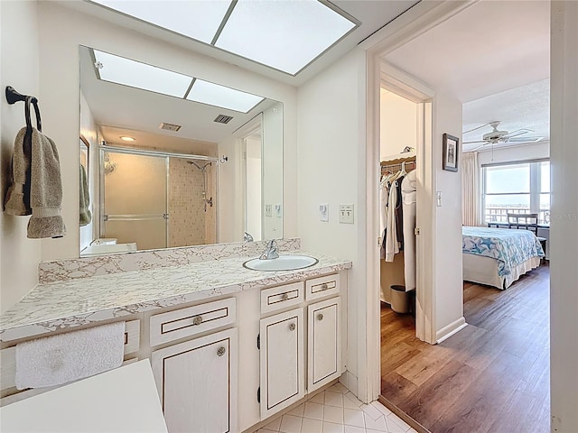 bathroom featuring vanity, wood finished floors, visible vents, a stall shower, and ceiling fan