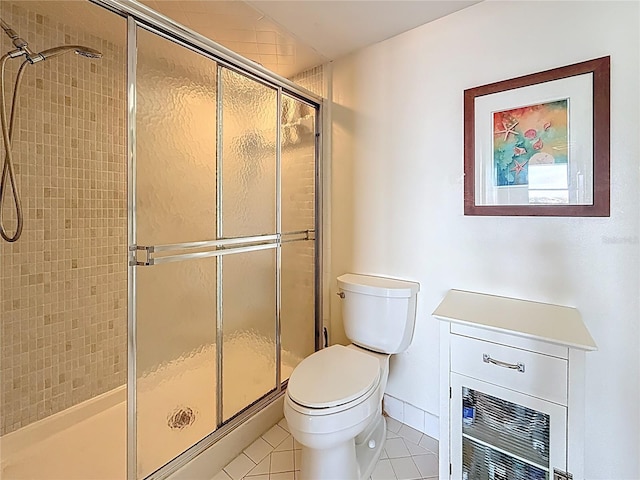 bathroom with tile patterned flooring, toilet, baseboards, and a stall shower