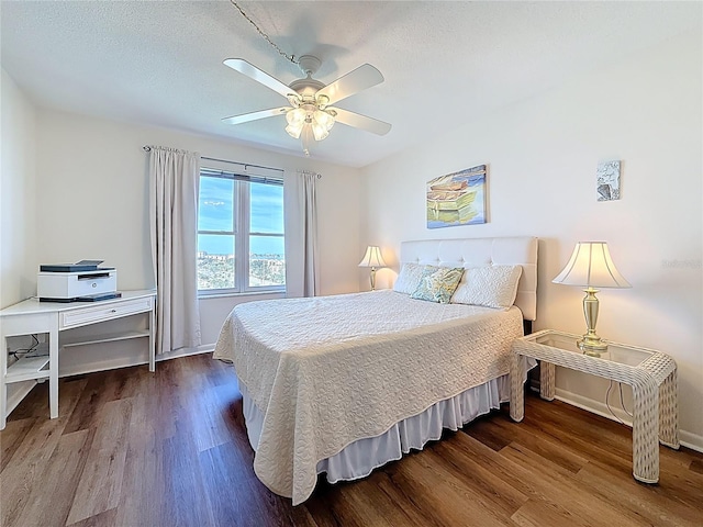 bedroom featuring baseboards, wood finished floors, and a ceiling fan