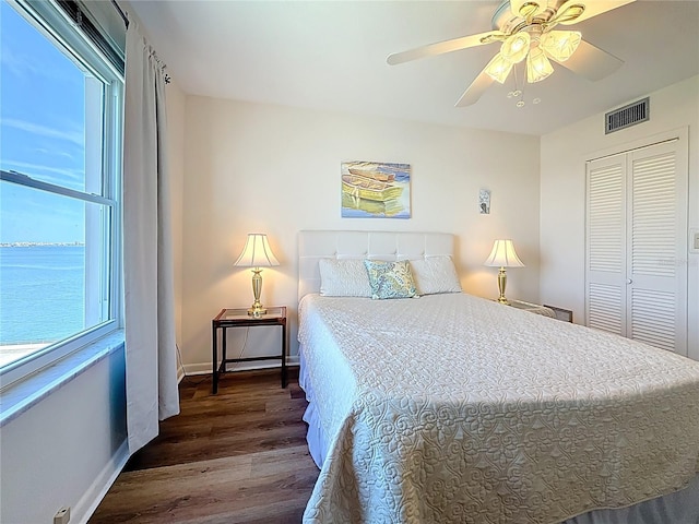 bedroom with visible vents, baseboards, wood finished floors, a closet, and a ceiling fan