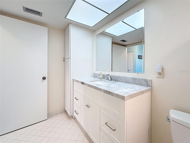 half bathroom featuring vanity, toilet, visible vents, and tile patterned flooring