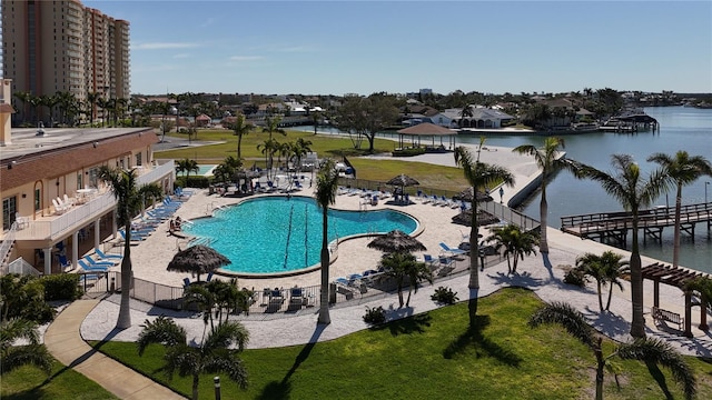 pool featuring a patio, fence, and a water view