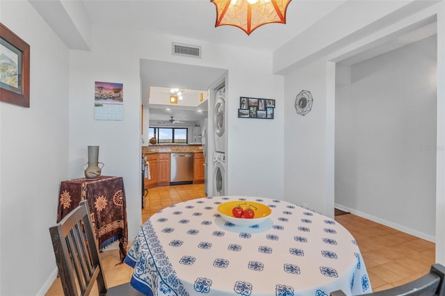 dining room with baseboards, light tile patterned floors, visible vents, and stacked washer / drying machine