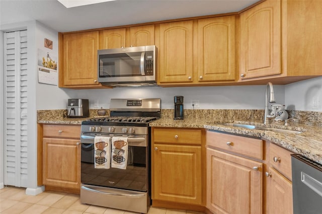 kitchen featuring light tile patterned floors, stainless steel appliances, a sink, light stone countertops, and light brown cabinetry