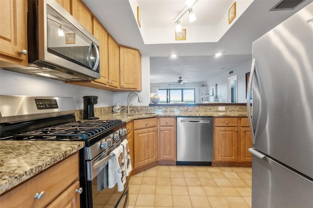 kitchen featuring light stone counters, stainless steel appliances, a sink, visible vents, and a tray ceiling