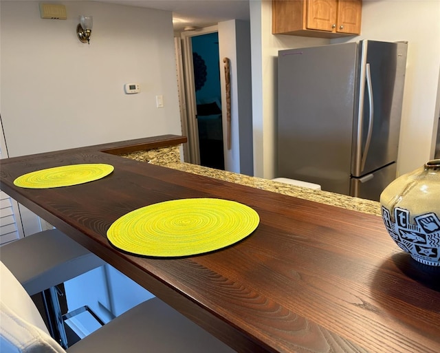 kitchen featuring brown cabinetry and freestanding refrigerator