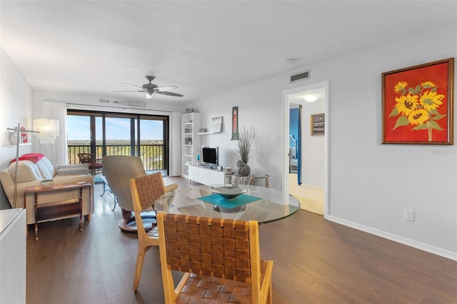 living room featuring ceiling fan, wood finished floors, visible vents, and baseboards