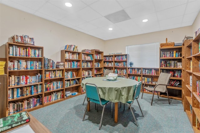 sitting room featuring carpet floors, bookshelves, a drop ceiling, and recessed lighting