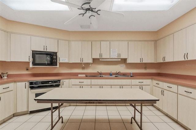 kitchen with light tile patterned floors, black microwave, a sink, and white oven