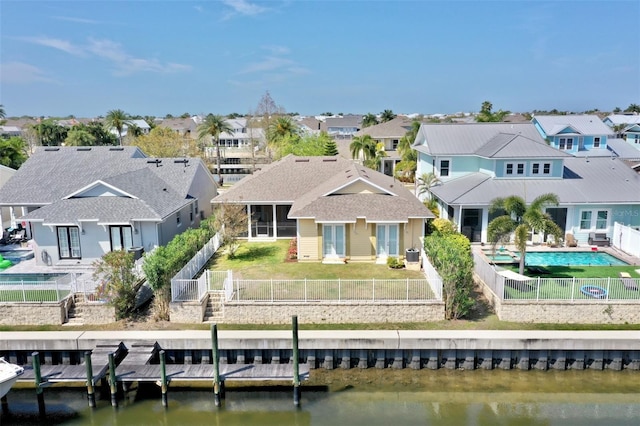 back of house featuring a water view, a fenced backyard, a residential view, and a lawn