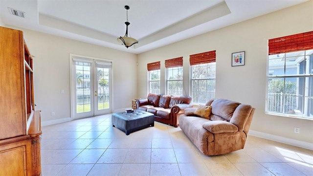 living area featuring french doors, a tray ceiling, light tile patterned flooring, and visible vents