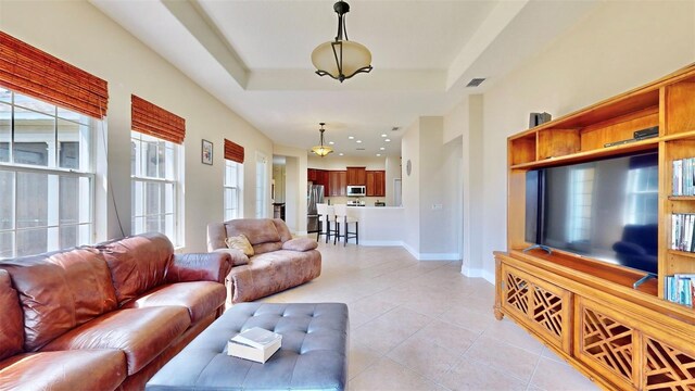 living room featuring baseboards, a tray ceiling, and light tile patterned flooring