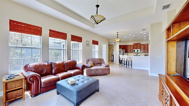 living room featuring light tile patterned floors, recessed lighting, visible vents, baseboards, and a tray ceiling