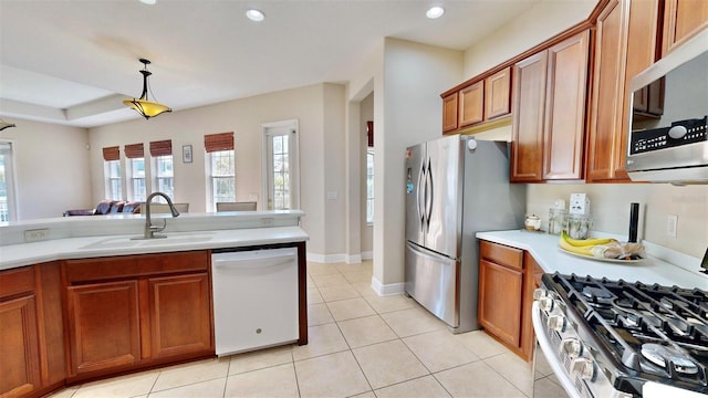 kitchen with light tile patterned flooring, a sink, light countertops, appliances with stainless steel finishes, and brown cabinets