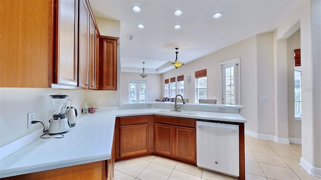 kitchen featuring white dishwasher, a peninsula, a sink, light countertops, and brown cabinetry