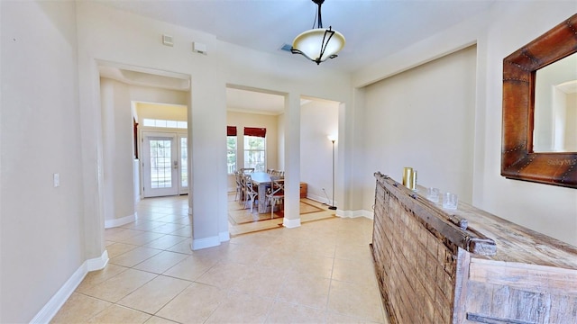 hallway featuring light tile patterned floors, french doors, and baseboards