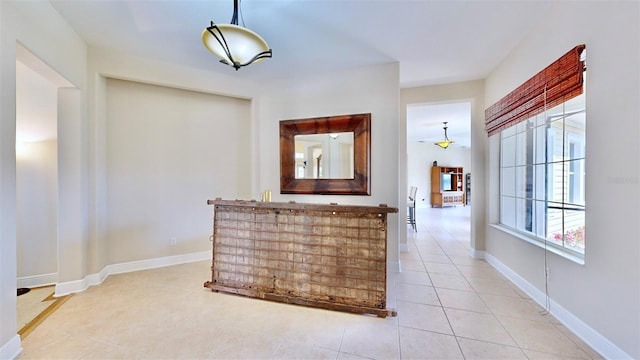 interior space featuring light tile patterned floors, hanging light fixtures, and baseboards