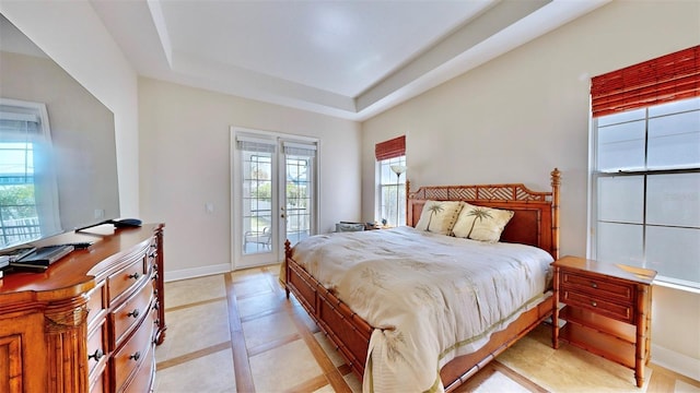 bedroom featuring access to outside, french doors, a raised ceiling, and baseboards