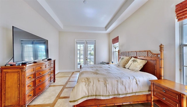 bedroom featuring baseboards, a tray ceiling, and access to outside