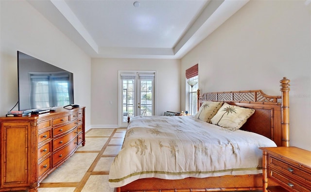 bedroom with access to exterior, a tray ceiling, french doors, and baseboards