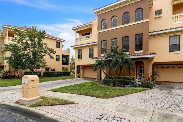 mediterranean / spanish home featuring an attached garage, a tile roof, decorative driveway, and stucco siding