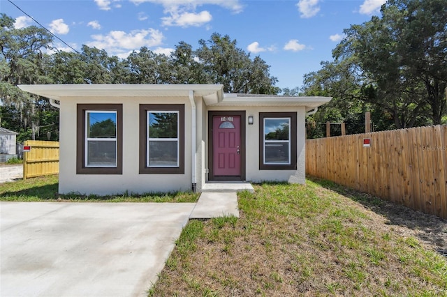 view of front of home with a front yard, fence, and stucco siding