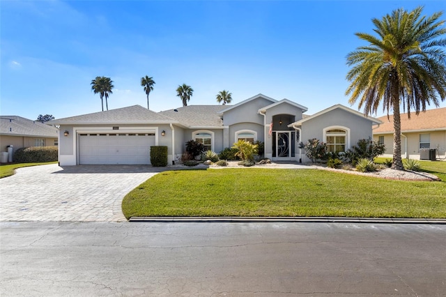 ranch-style home featuring a garage, decorative driveway, a front yard, and stucco siding