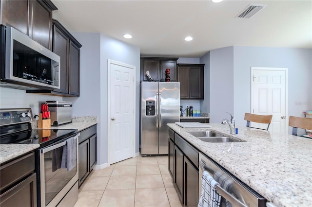 kitchen featuring light tile patterned floors, light stone counters, a sink, visible vents, and appliances with stainless steel finishes