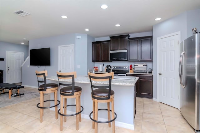 kitchen with appliances with stainless steel finishes, recessed lighting, visible vents, and a breakfast bar