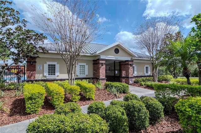 ranch-style house featuring a standing seam roof, brick siding, metal roof, and stucco siding