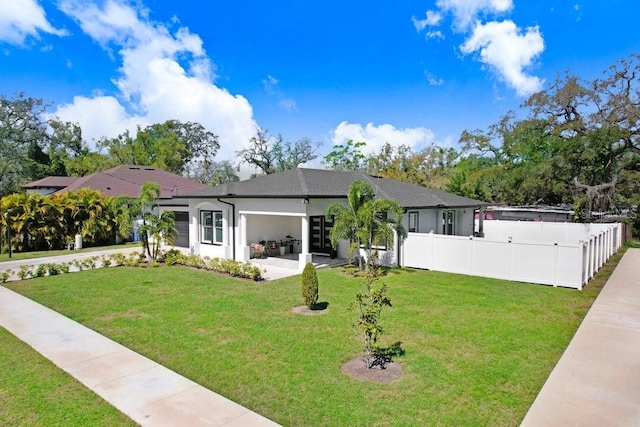 view of front of house with a patio area, fence, a front lawn, and stucco siding