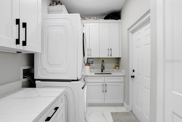 laundry area with stacked washing maching and dryer, cabinet space, marble finish floor, and a sink