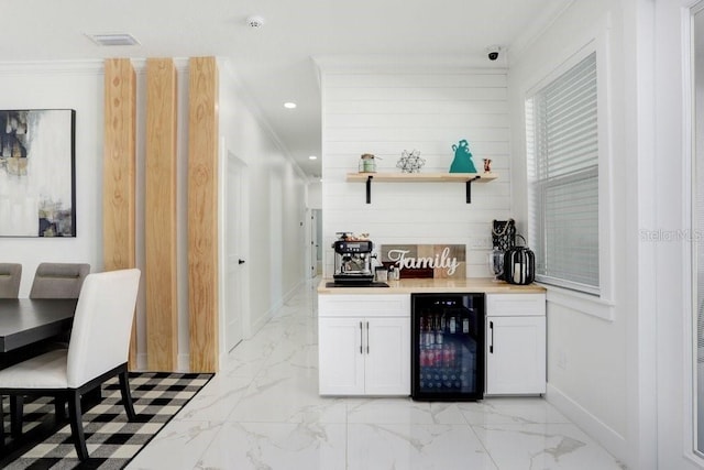 bar featuring a dry bar, marble finish floor, beverage cooler, and ornamental molding