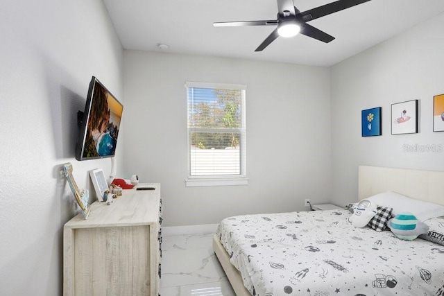 bedroom featuring ceiling fan, marble finish floor, and baseboards