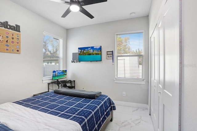 bedroom with ceiling fan, marble finish floor, a closet, and baseboards