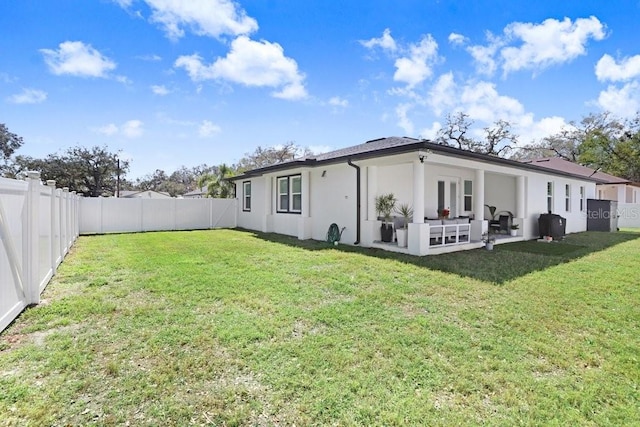 rear view of property with a patio, a lawn, a fenced backyard, and stucco siding