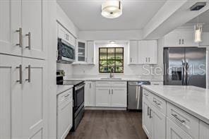 kitchen with white cabinets, stainless steel appliances, dark wood finished floors, and light countertops