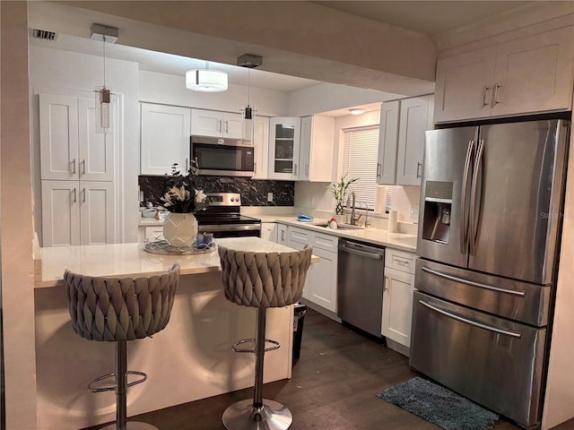 kitchen with light countertops, appliances with stainless steel finishes, a breakfast bar, and white cabinets