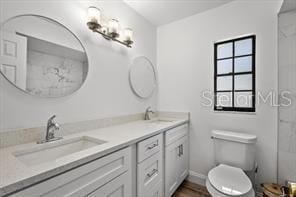 full bath featuring double vanity, a sink, and toilet