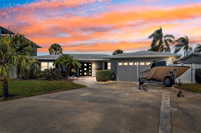 view of front facade featuring a garage, driveway, fence, and stucco siding