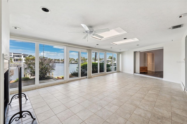 interior space with a water view, a skylight, visible vents, and a wealth of natural light