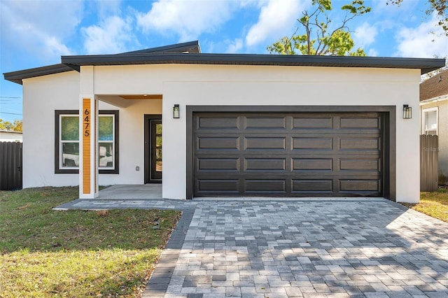 contemporary home with an attached garage, decorative driveway, and stucco siding