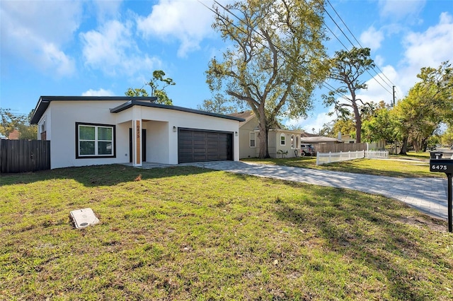 view of front of property featuring stucco siding, fence, a garage, driveway, and a front lawn