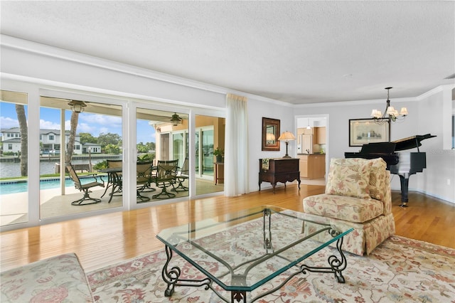 living room with a textured ceiling, crown molding, wood finished floors, and an inviting chandelier