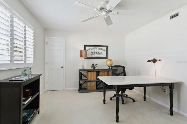 office space featuring visible vents, baseboards, light colored carpet, ceiling fan, and a textured ceiling