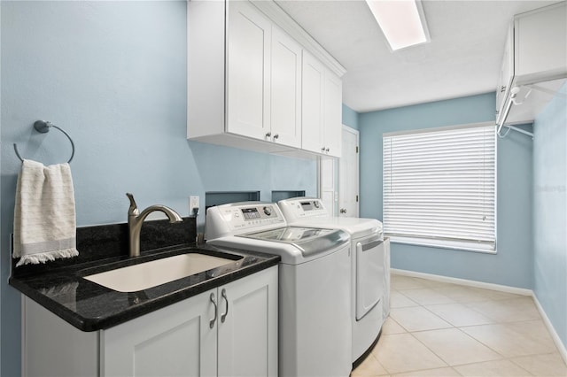 clothes washing area featuring light tile patterned flooring, washing machine and dryer, a sink, baseboards, and cabinet space